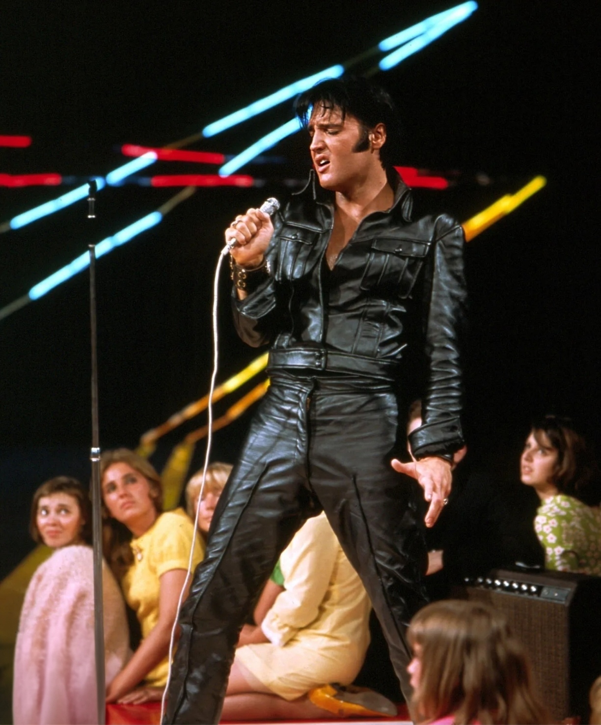 Elvis Presley cantando con su traje de cuero negro ante el público